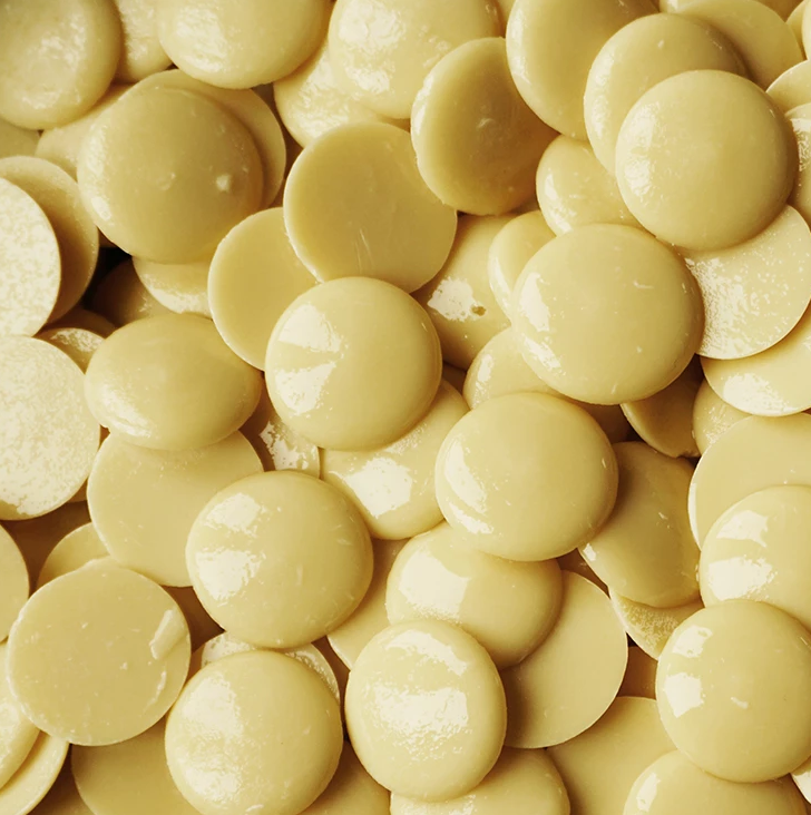 A bag of JM Posner’s vegan white chocolate buttons, labeled as dairy-free, gluten-free, soya-free, and made with Rainforest Alliance-certified chocolate.