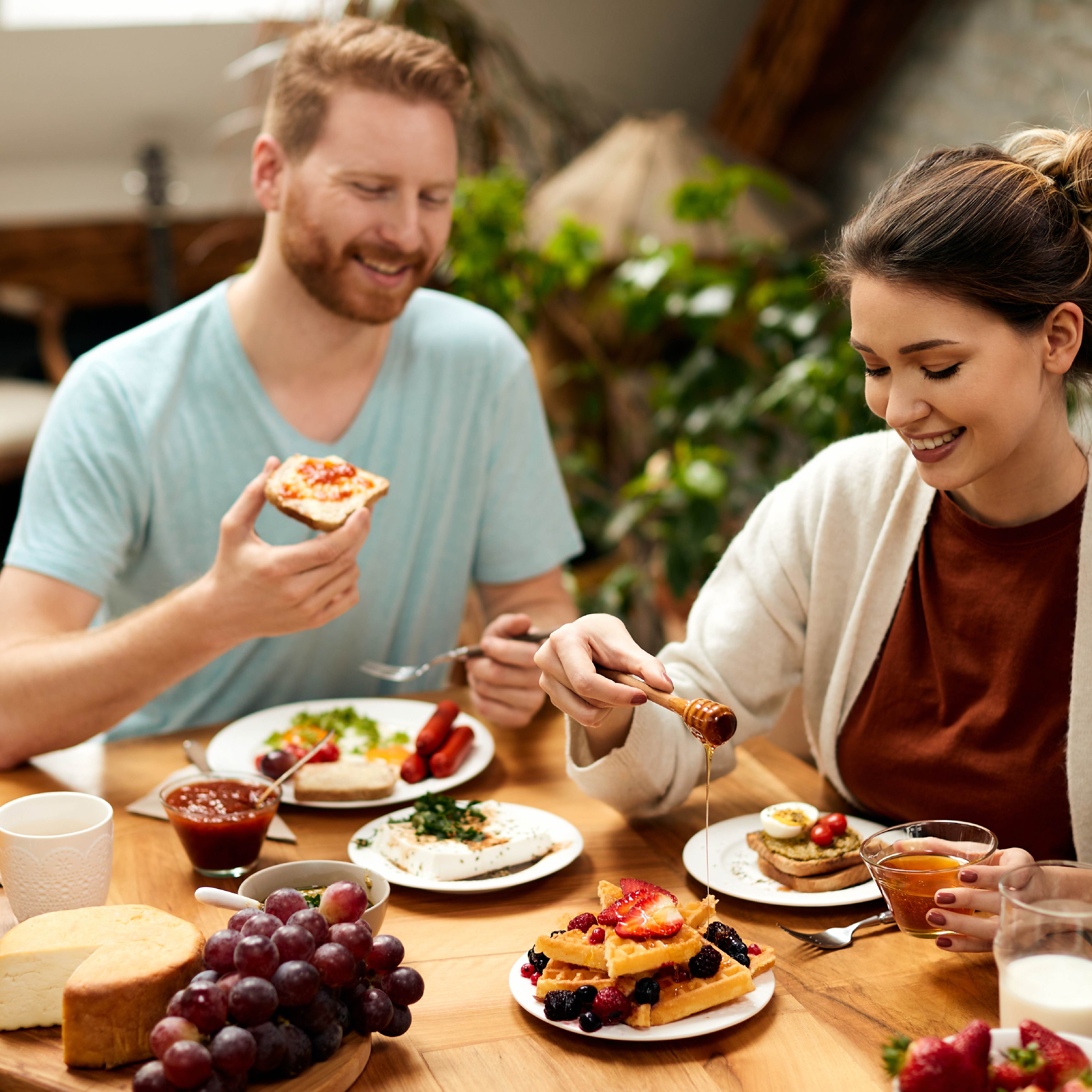 Man and woman eating waffles with different toppings