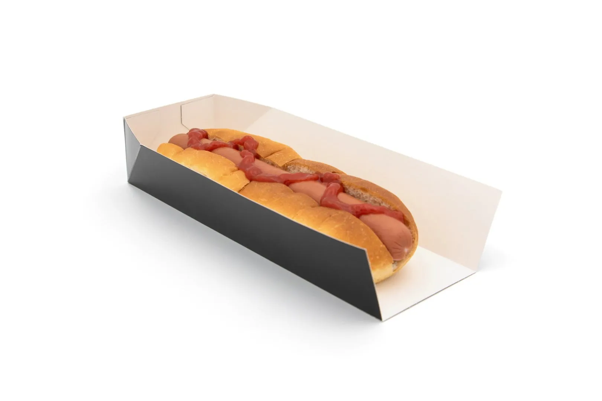 A hot dog in a soft bun topped with ketchup, placed in a black-and-white cardboard hot dog tray on a white background.