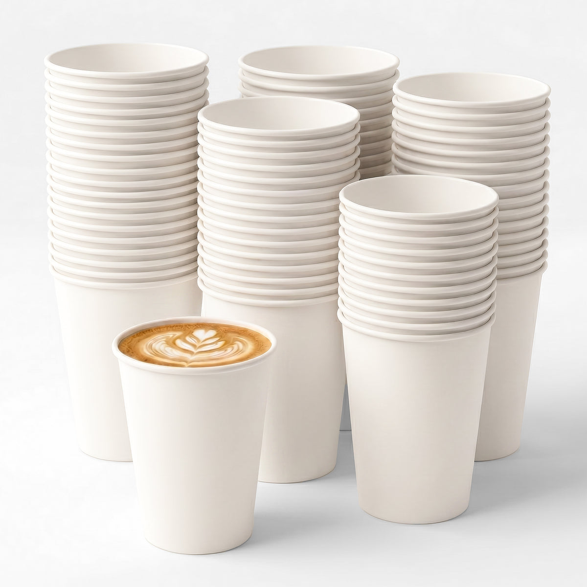 A stack of white disposable cups with one cup in front containing latte art.