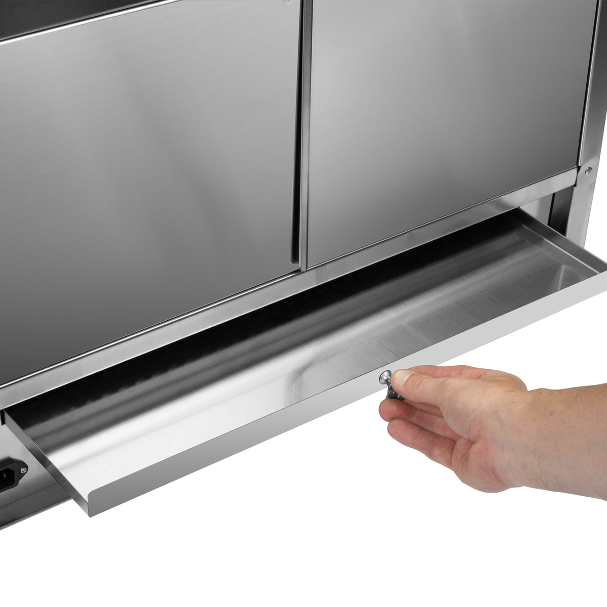 Hand pulling open a stainless steel drip tray from the bottom of a commercial appliance.