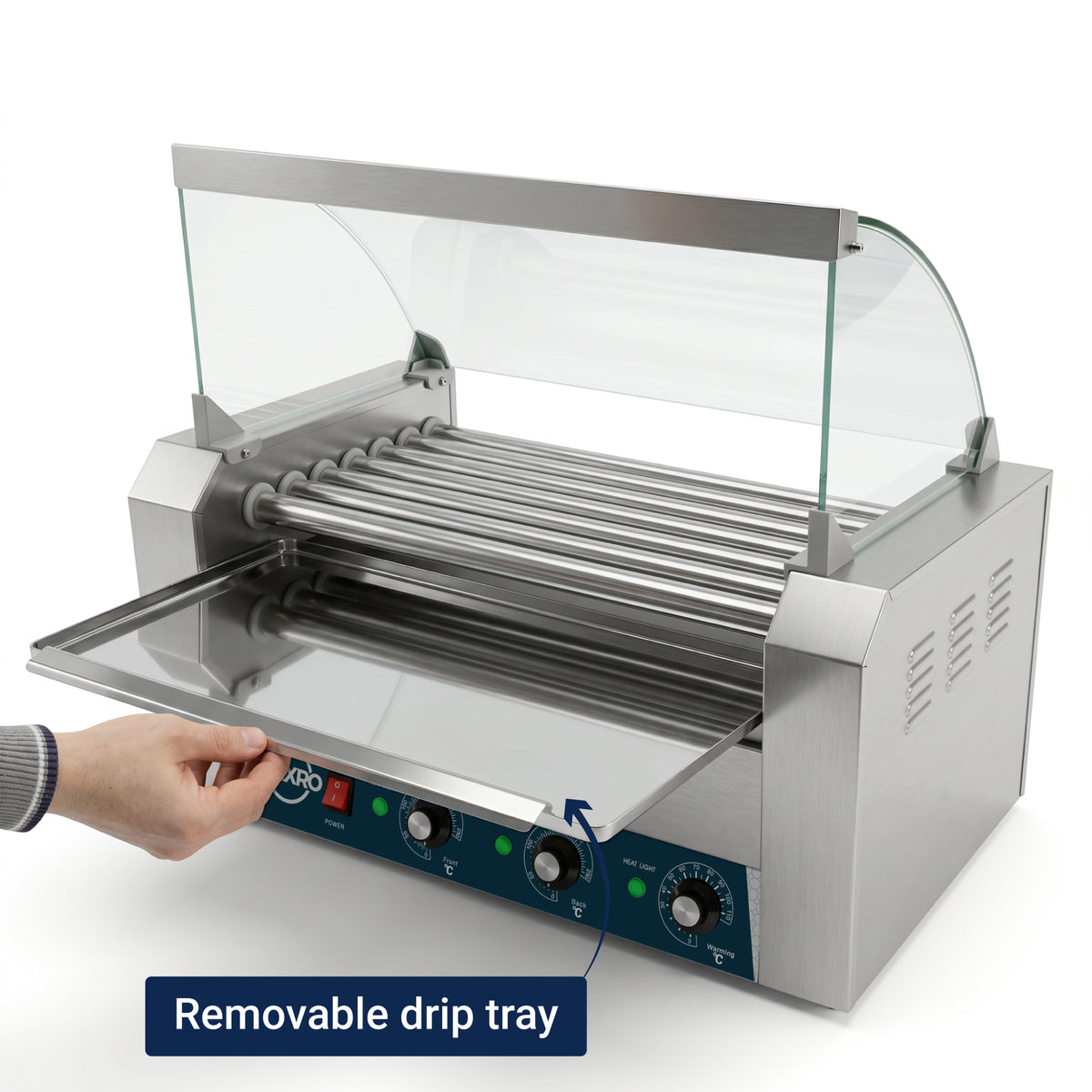 Stainless steel hot dog roller grill with glass canopy. A hand pulls out the removable drip tray. Control knobs and lights are on the front panel.
