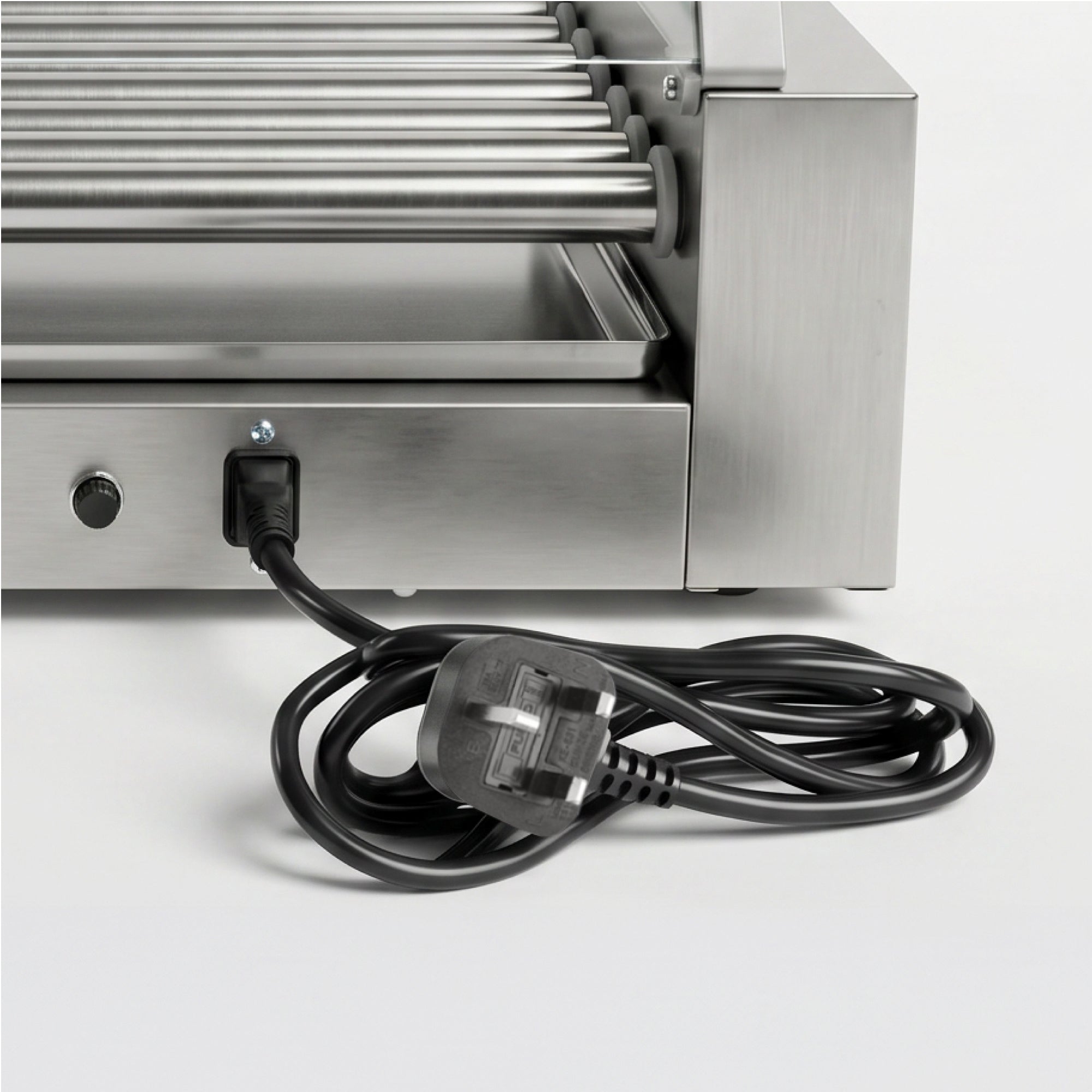 Close-up of a stainless steel hot dog roller machine with several rollers, a control knob, and an attached black power cord on a white surface.