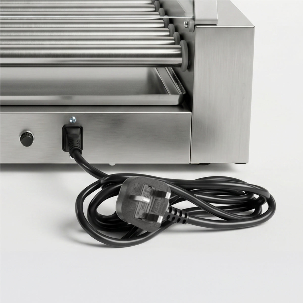 Close-up of a stainless steel hot dog roller machine with several rollers, a control knob, and an attached black power cord on a white surface.