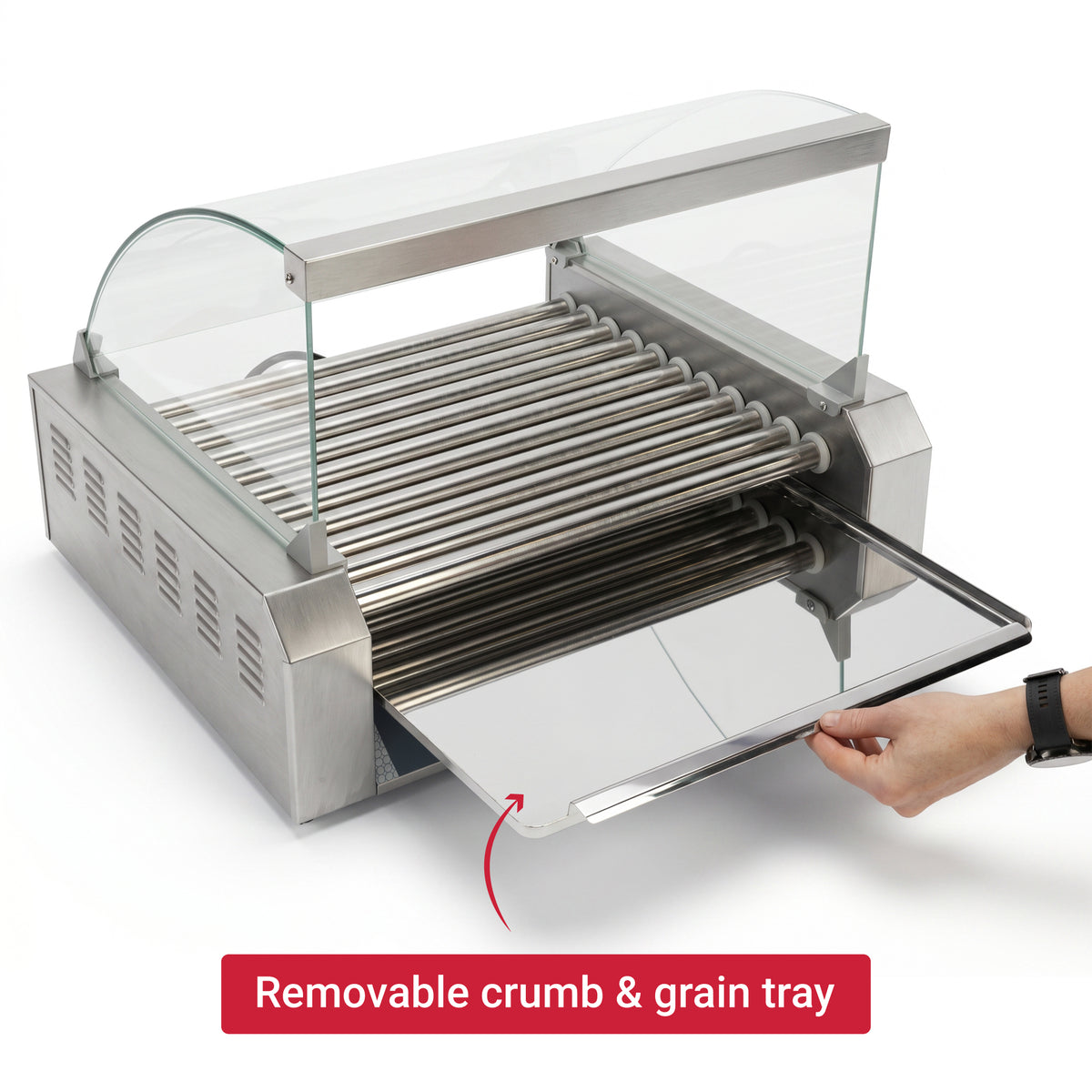 A stainless steel hot dog roller with a transparent cover is shown. A hand pulls out a removable crumb and grain tray. A red label highlights this feature.