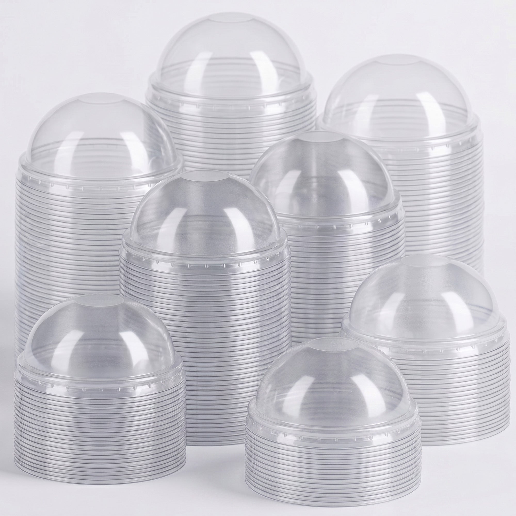 Stacks of clear plastic cups with dome lids are arranged closely together against a white background, conveying a clean, organized appearance.