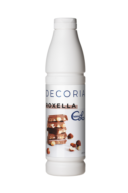 Close-up of a white bottle labeled "Decoria Roxella" featuring stacked chocolate bars with hazelnuts on the label, isolated on a white background.
