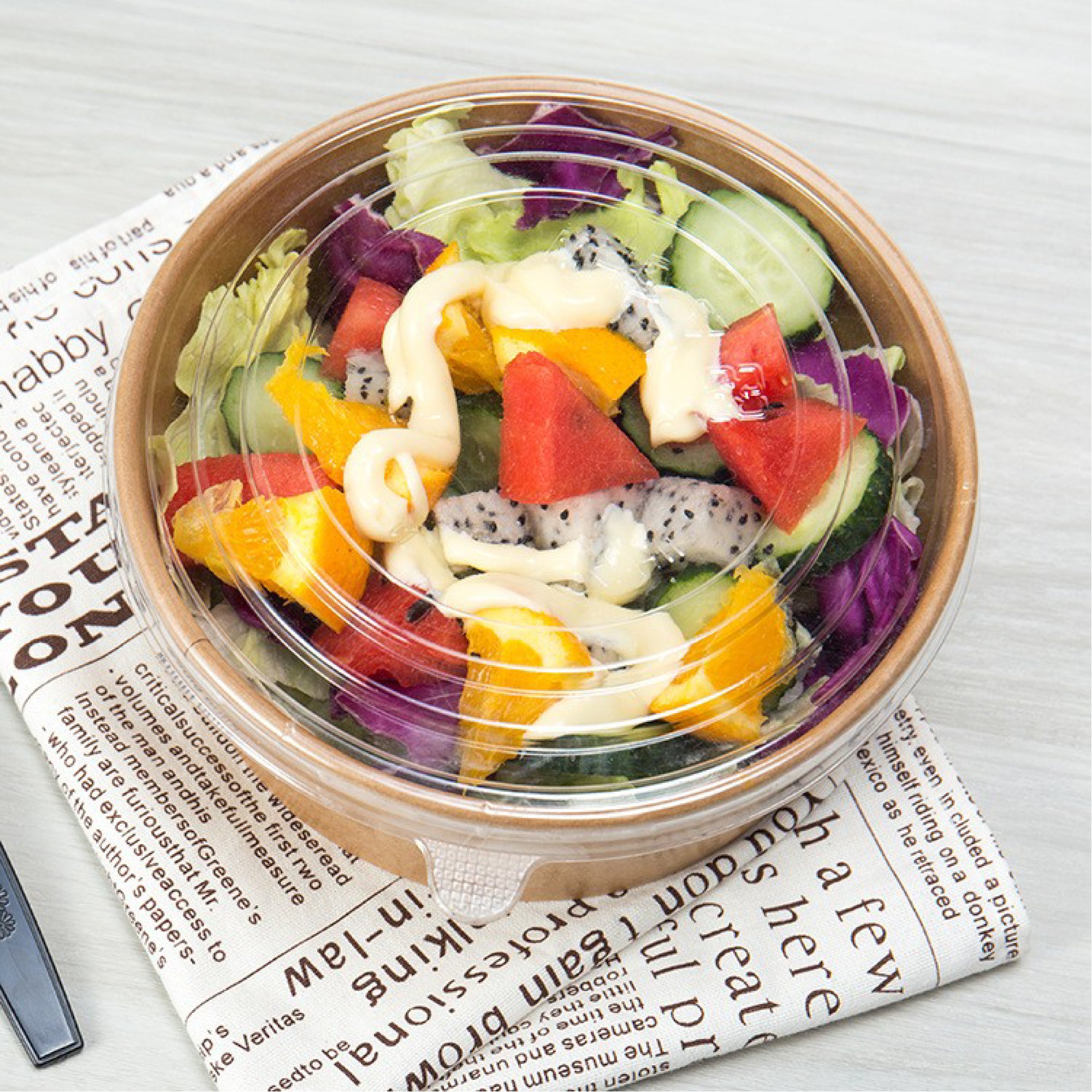 Colorful salad in a clear container on a newspaper background