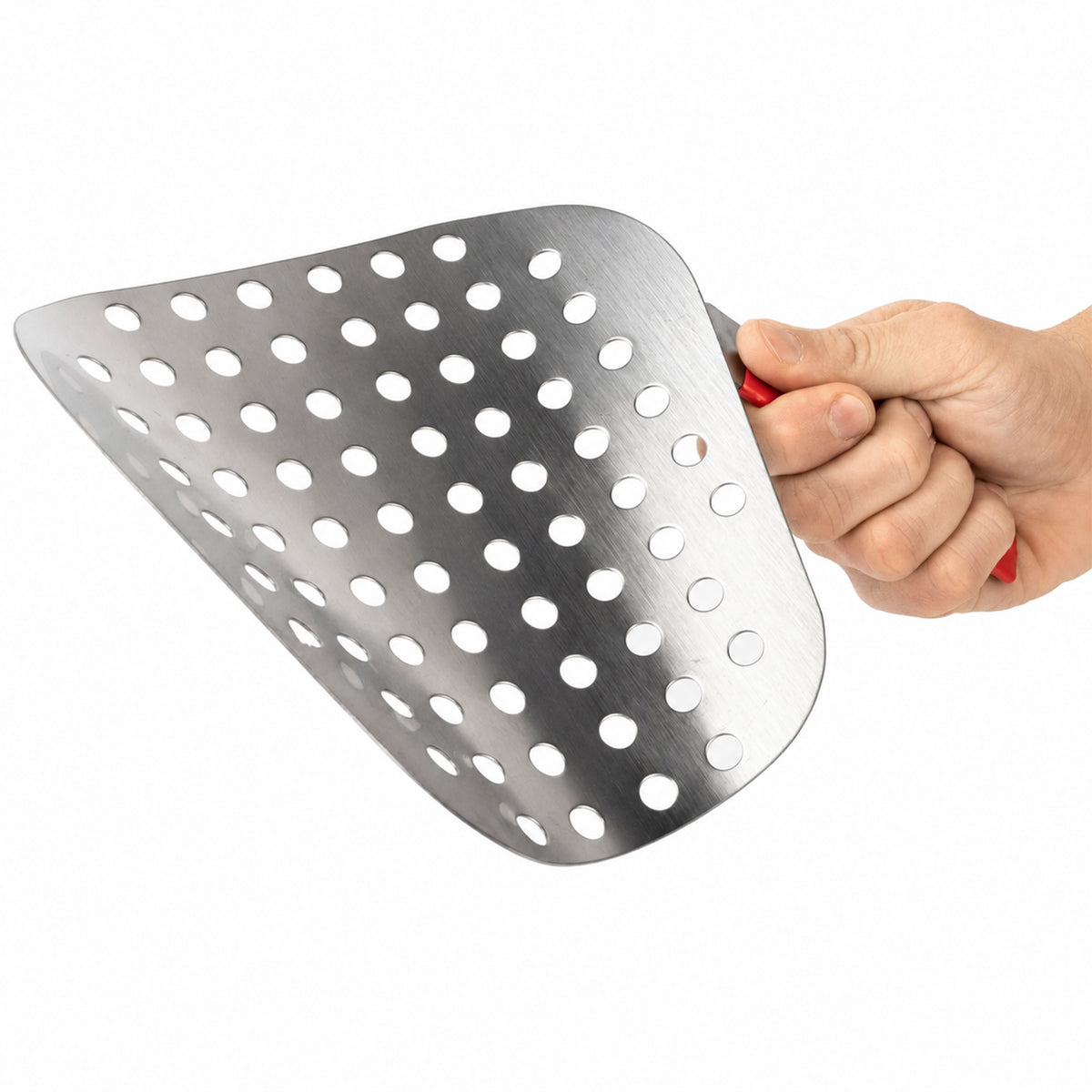A hand holding a stainless steel slotted spatula with a red handle.