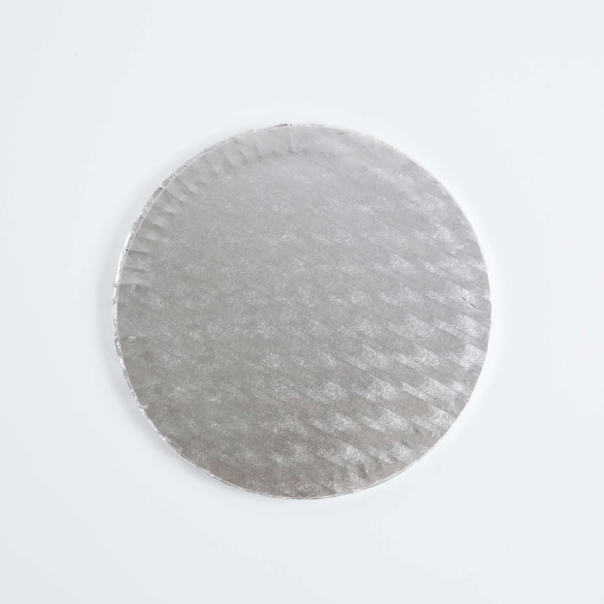 A round silver cake board with a textured, embossed pattern, photographed from directly above on a clean white background.