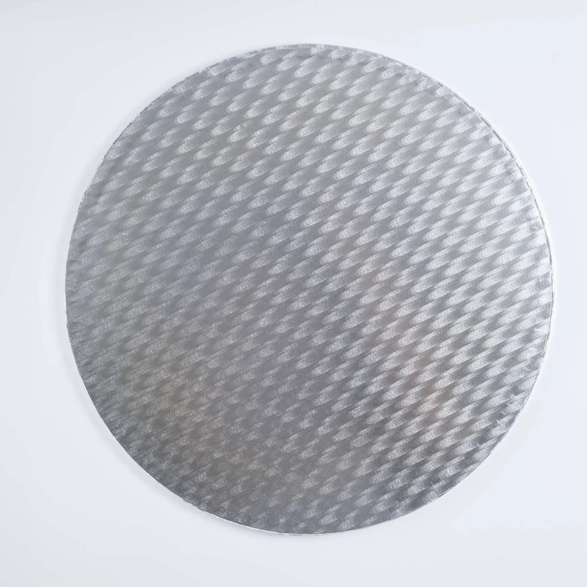 A round silver cake board with a textured, woven carbon-fiber-like pattern, shown against a plain white background.