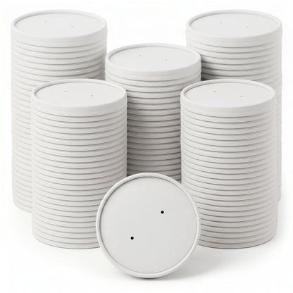 Stacks of round, white coasters with smooth surfaces are neatly arranged. One coaster leans in front, showing two small holes. The tone is clean and minimalist.