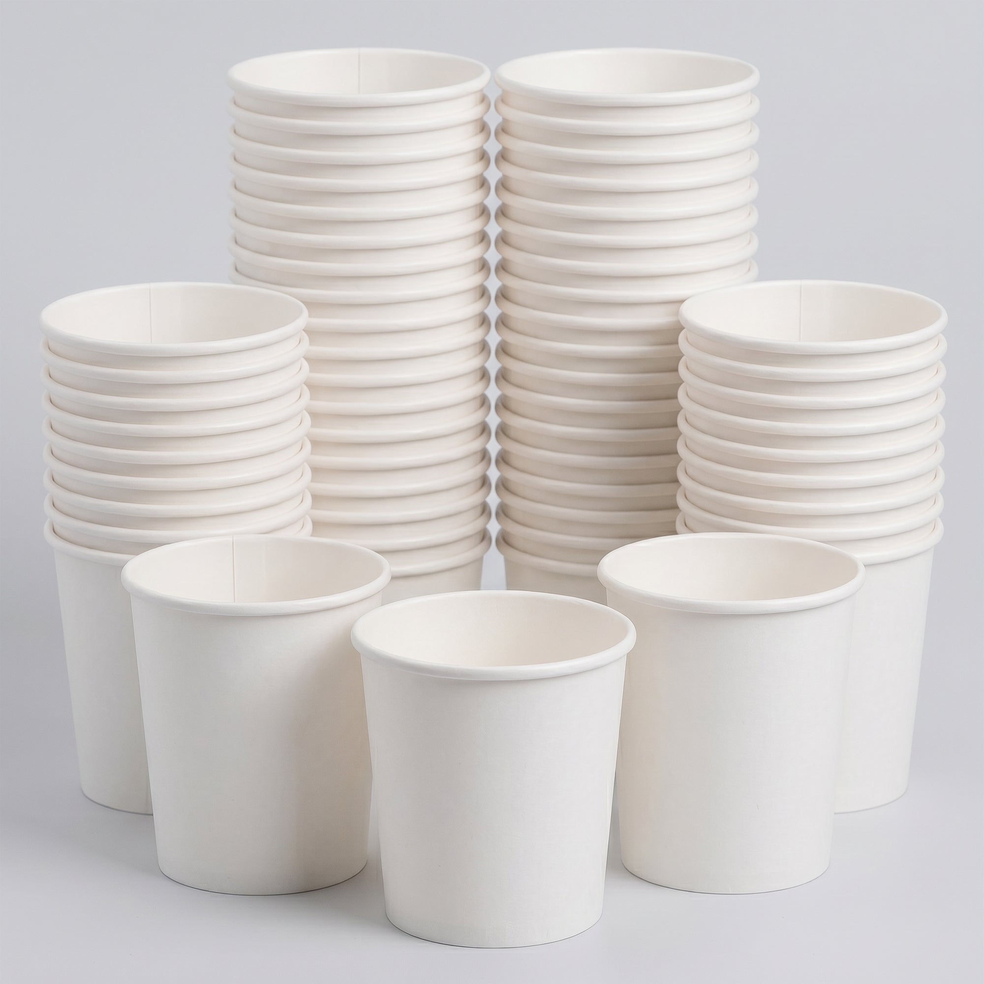 Stacks of white disposable paper cups are arranged in rows against a plain background. The cups convey a clean, organized, and minimalistic tone.