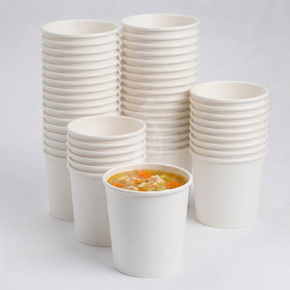A stack of white paper cups with one filled with steaming chicken noodle soup, featuring carrots and noodles, creating a warm, comforting atmosphere.