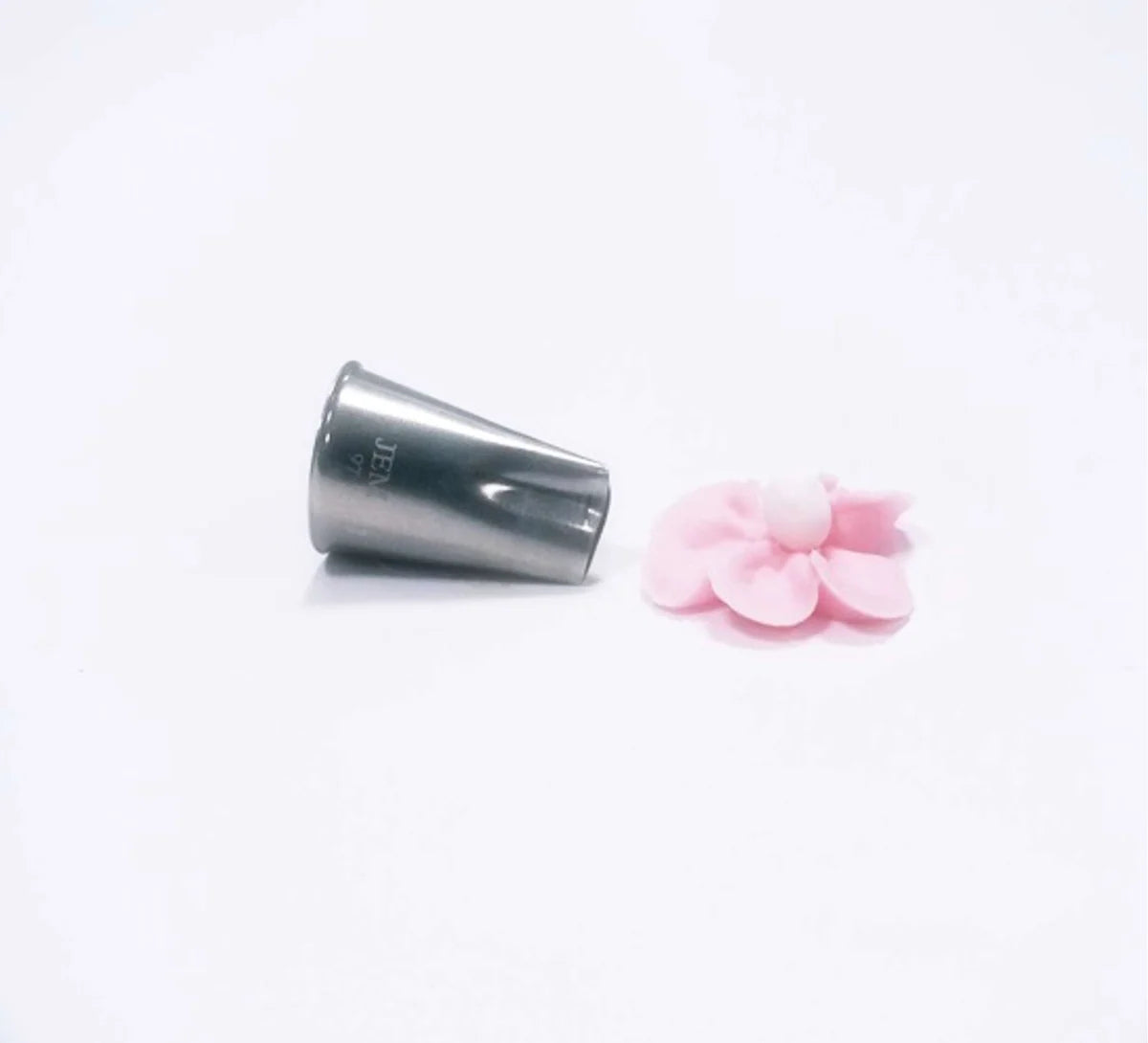 A stainless steel piping tip shown next to a small pink flower-shaped decoration on a plain white background.