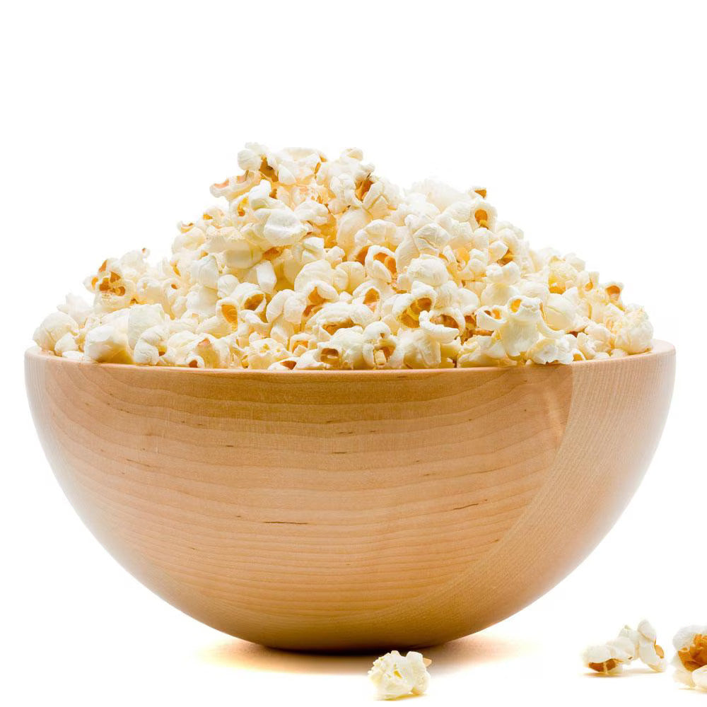 A wooden bowl filled with fluffy popcorn, some kernels scattered around.