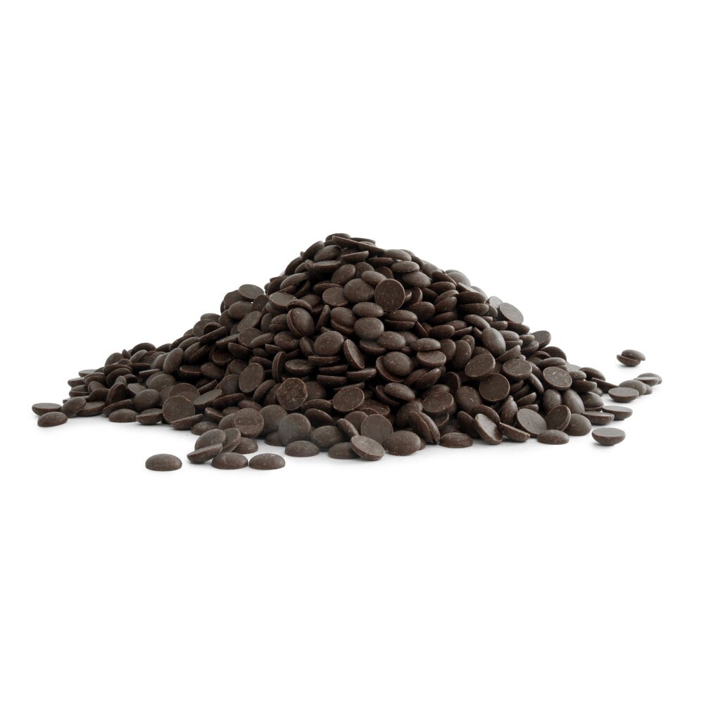 A pile of dark chocolate callets or chips arranged on a white surface.