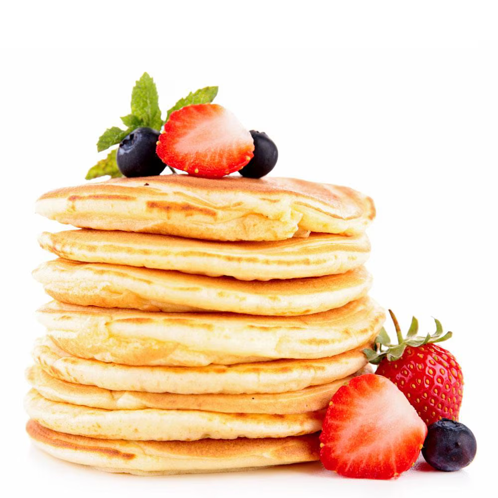 A stack of golden pancakes topped with fresh strawberries, blueberries, and a sprig of mint. The pancakes are perfectly round and fluffy, with vibrant red and blue berries placed on top.