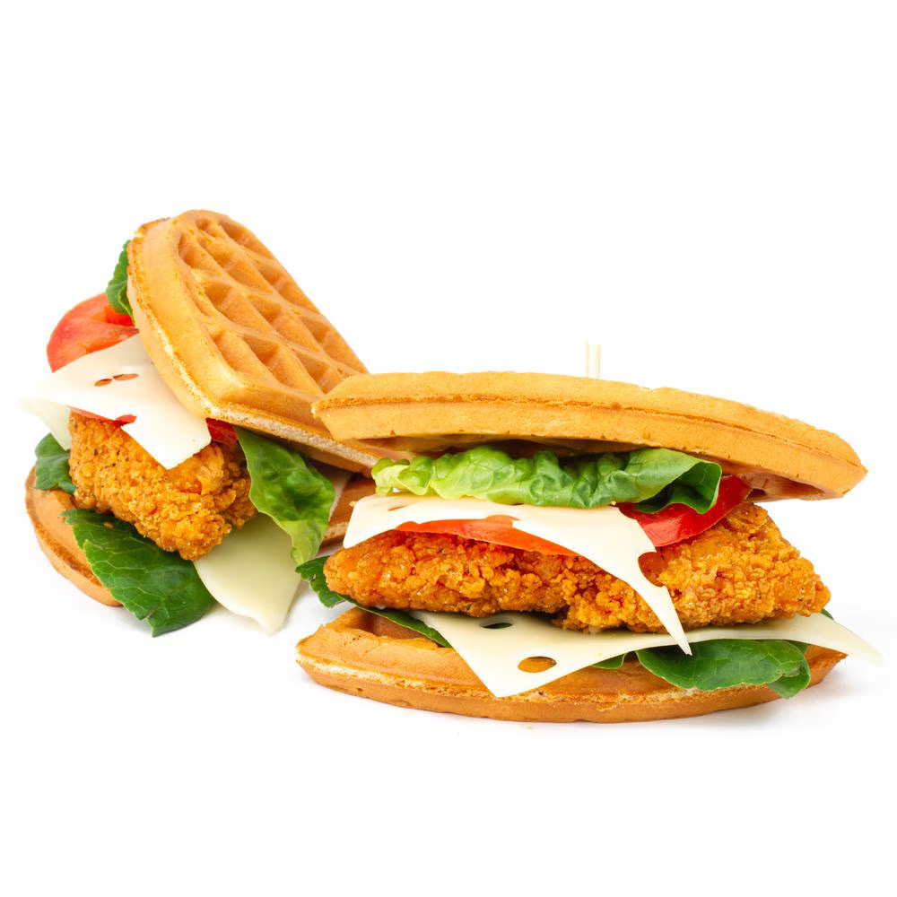 Two crispy fried chicken fillets served in waffle sandwiches with lettuce, tomato slices, and cheese on a white background.