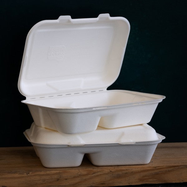 Two stacked compostable food containers with lids, placed on a wooden surface against a dark background.
