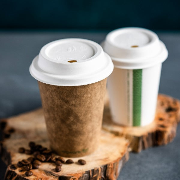 Two paper coffee cups with white lids on a wooden surface with coffee beans.