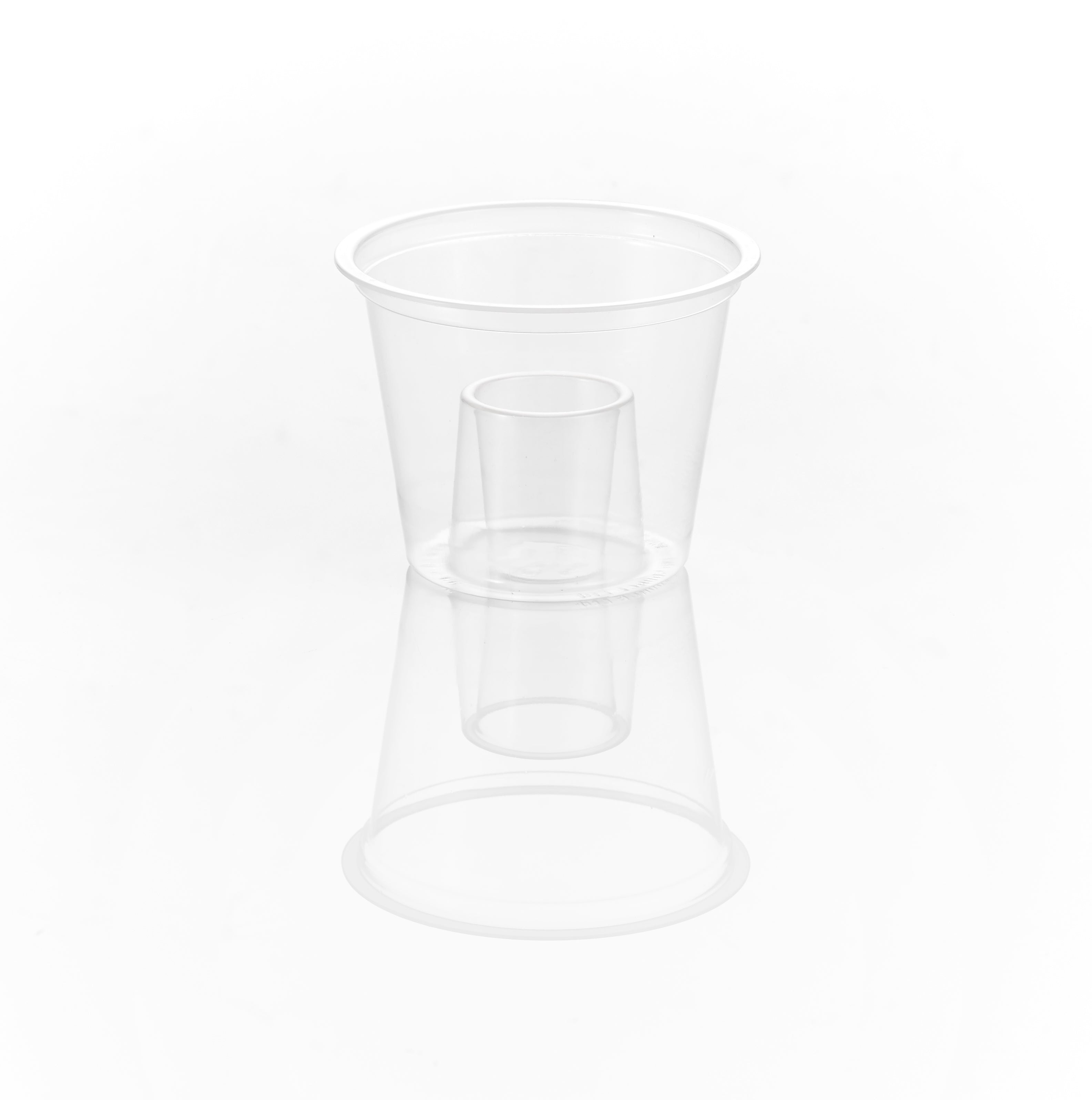 A clear plastic cup, with a smaller clear plastic cup inside it, reflecting on a white surface.