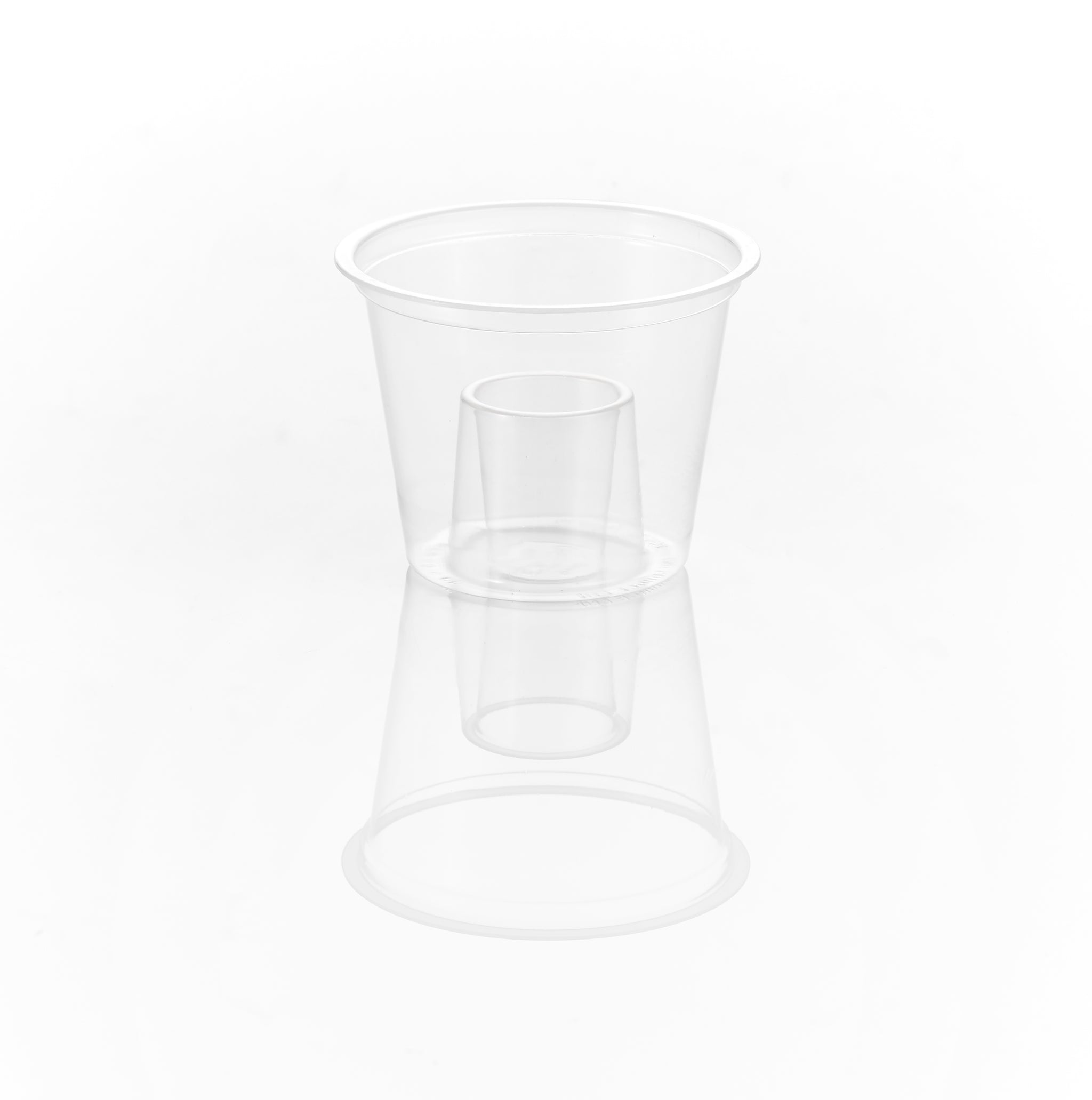 A clear plastic cup, with a smaller clear plastic cup inside it, reflecting on a white surface.