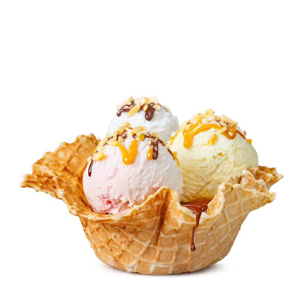 A waffle cone basket filled with three scoops of ice cream in different flavors, topped with chocolate and caramel syrup, and sprinkled with nuts.
