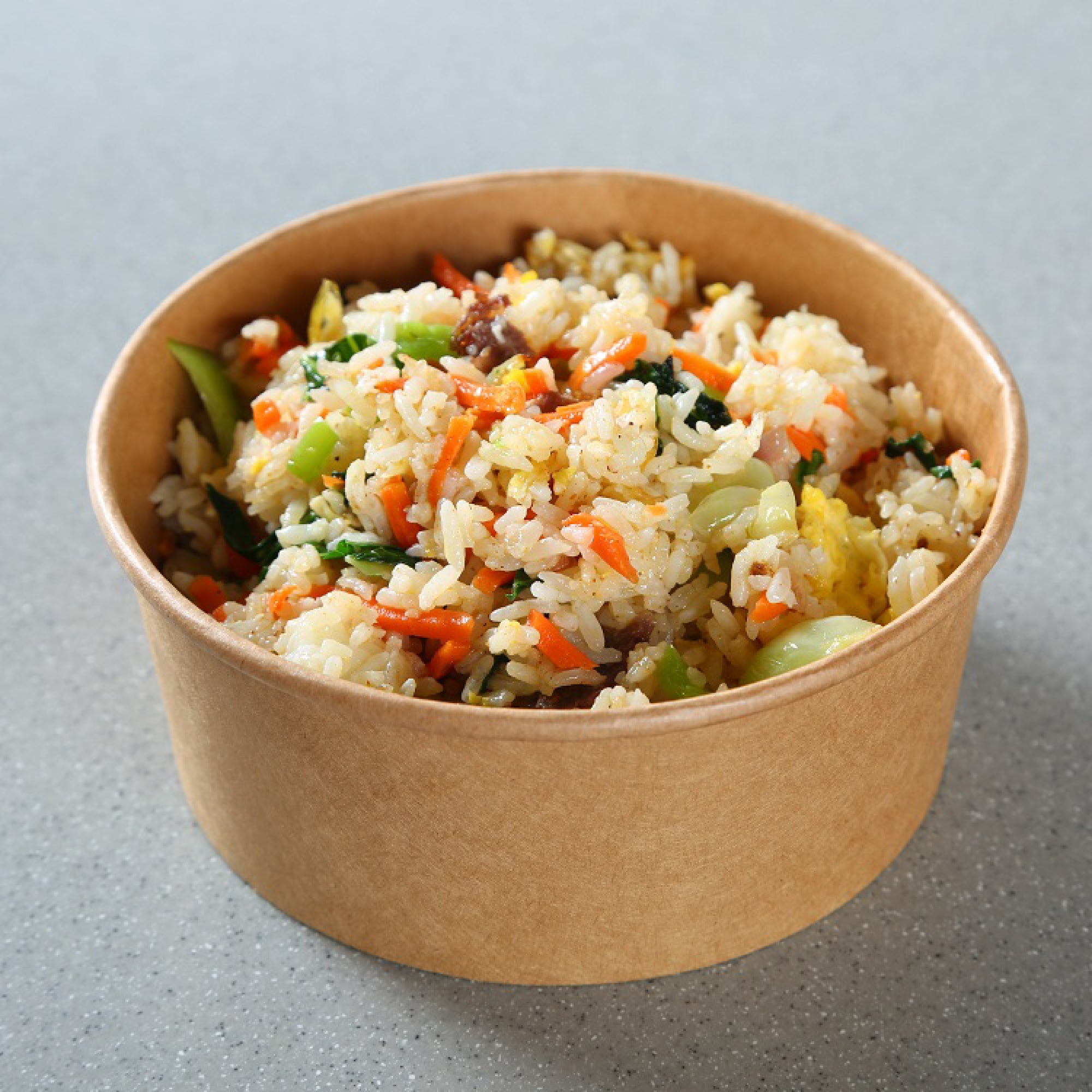 Brown paper bowl filled with fried rice on a gray background