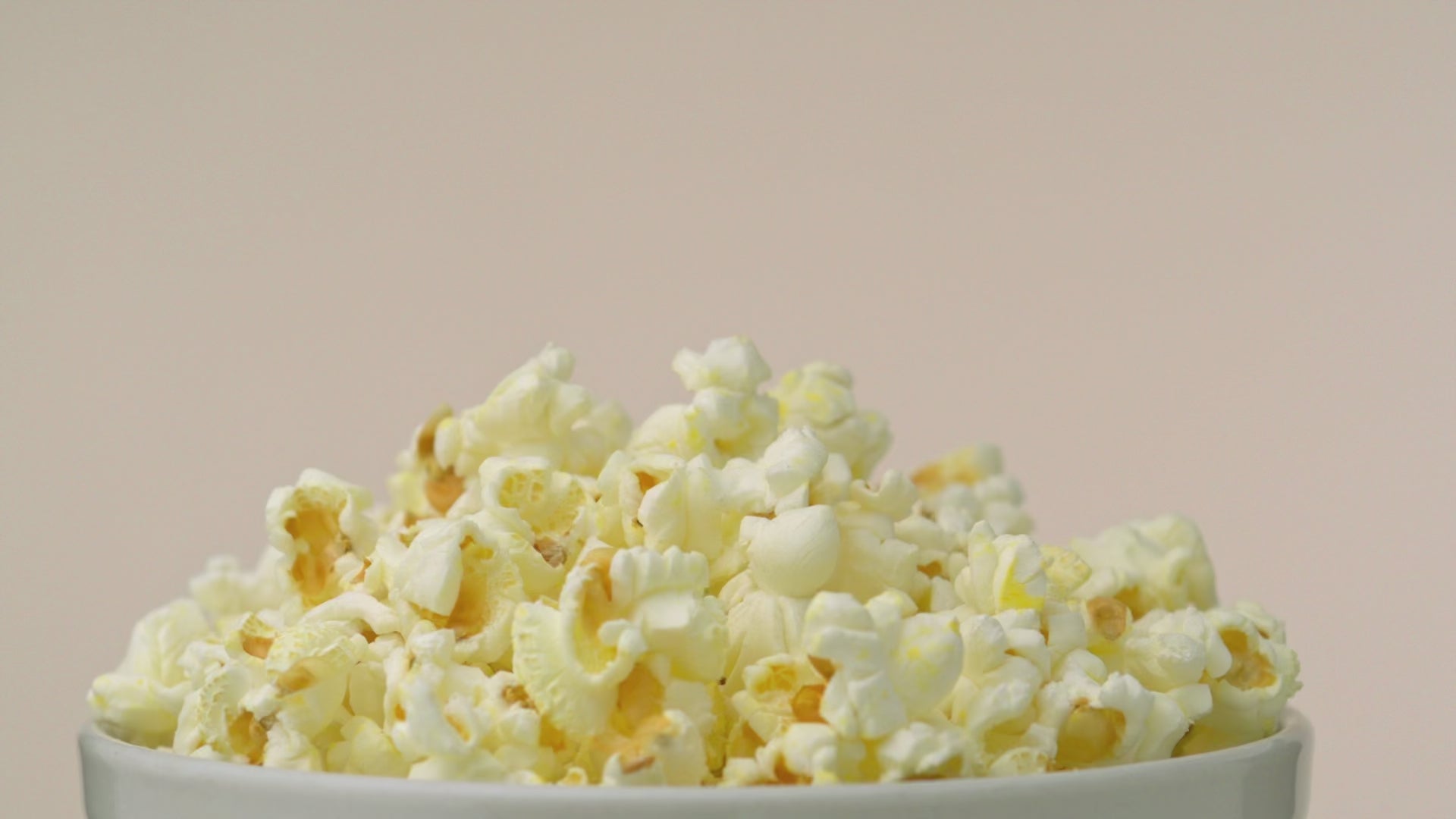 Flavacol salt being sprinkled over fresh popcorn for classic buttery flavor.