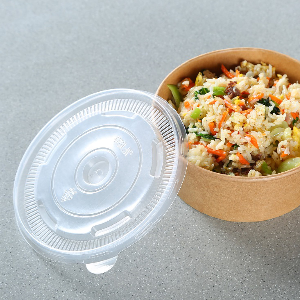 A takeout container filled with rice and vegetables, with a clear lid partially covering it.