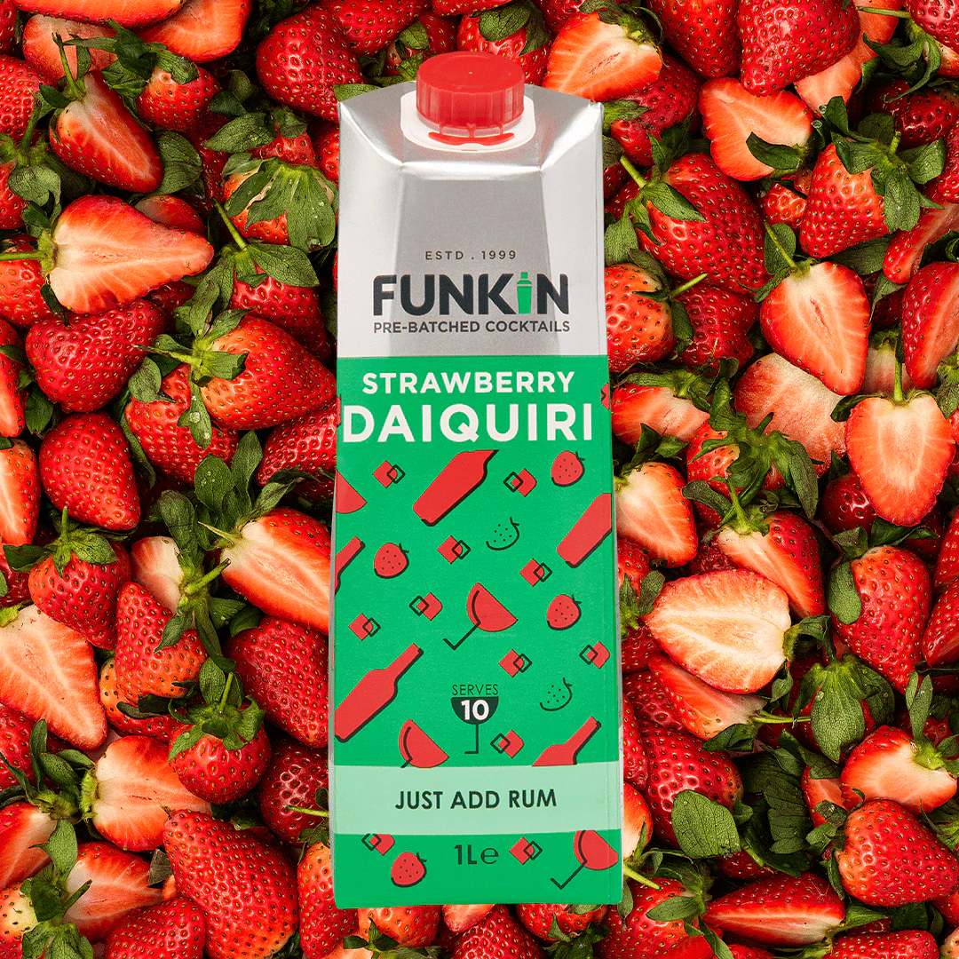 A Funkin Strawberry Daiquiri cocktail mixer carton positioned upright on a large pile of fresh whole and halved strawberries.
