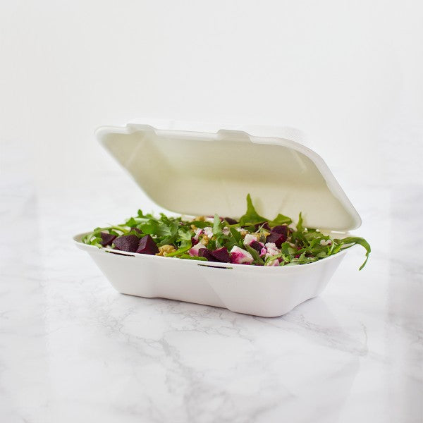 Salad in a take-out container on a white marble surface