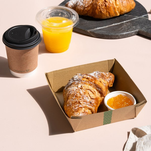 Breakfast set with croissants, coffee, and orange juice on a light pink background