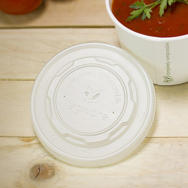 Plastic lid with 'Legnum' branding on a wooden surface next to a bowl of soup.
