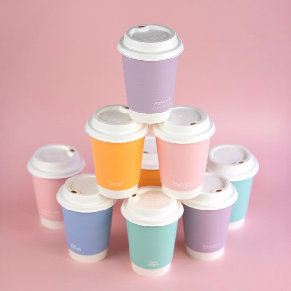 Stack of colorful paper cups with lids on a pink background