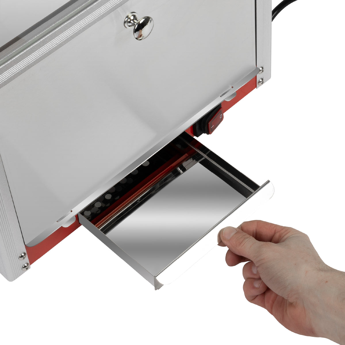 A hand pulling out a metal drawer from a machine with a silver and red exterior.
