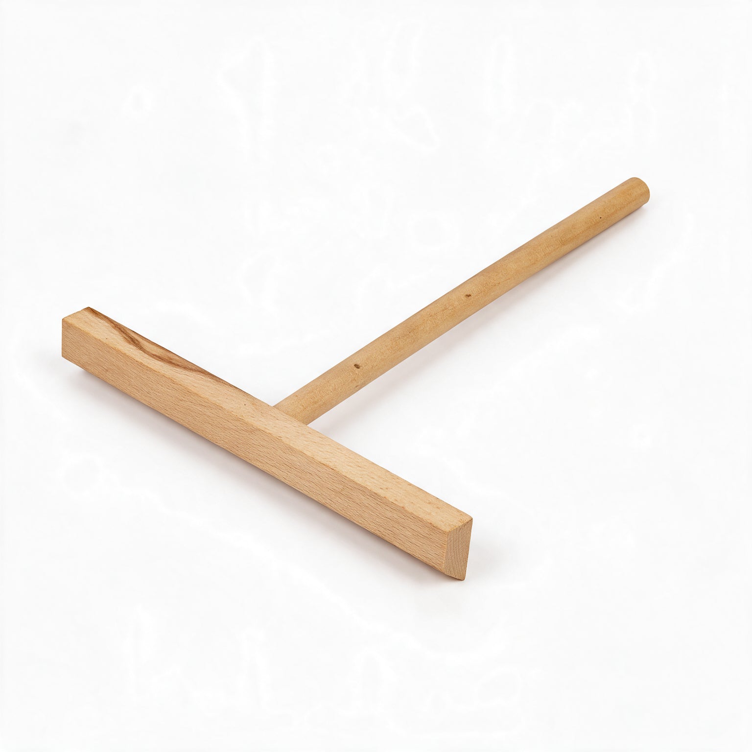 A simple wooden T-shaped tool lies on a white background, with a long narrow handle joined to a broad crosspiece; its natural finish feels handmade.